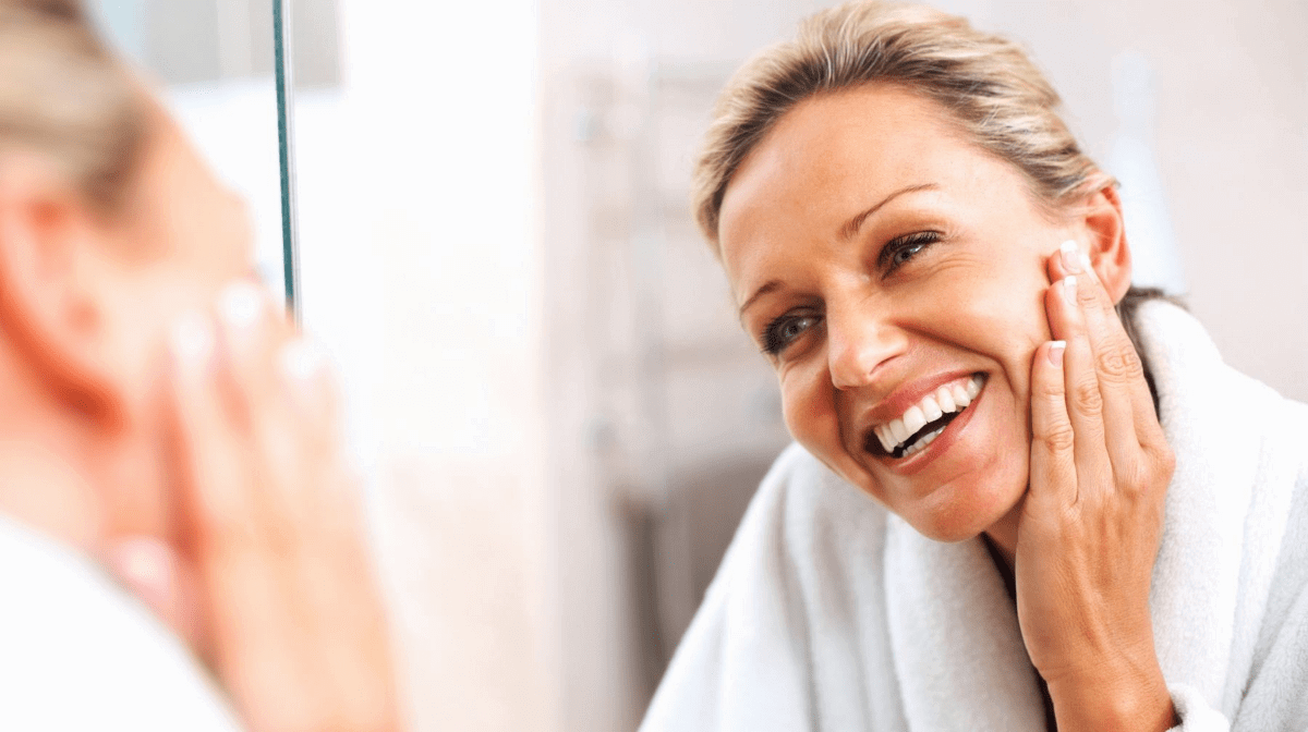 Woman smiling at herself in the mirror checking her face