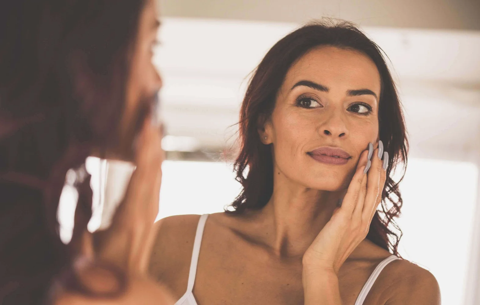 Woman looking at her face in the mirror